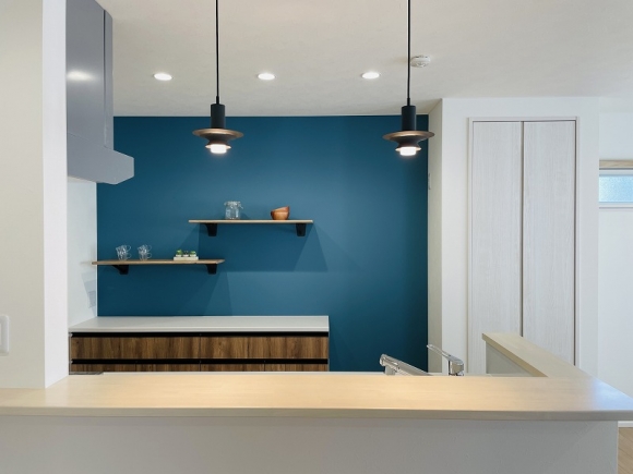 キッチン背面は外観に合わせたブルーのクロスに造作で棚を作りつけた可愛らしいデザインに♪